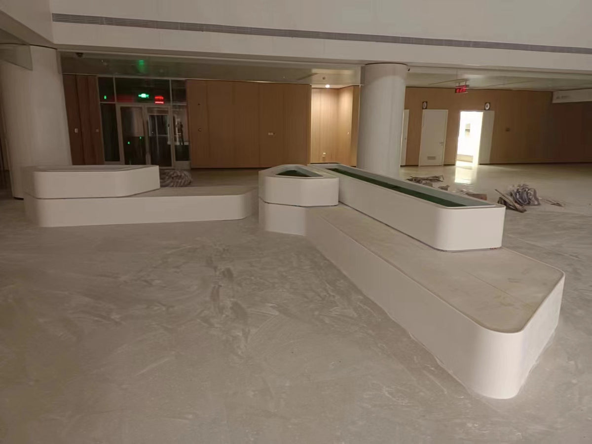 Long white counter forms with curved ends in an unfinished interior