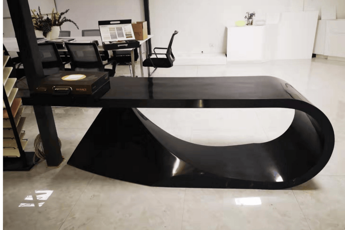 Side view of red sculptural solid surface executive desk for creative offices with seamless acrylic solid surface finish