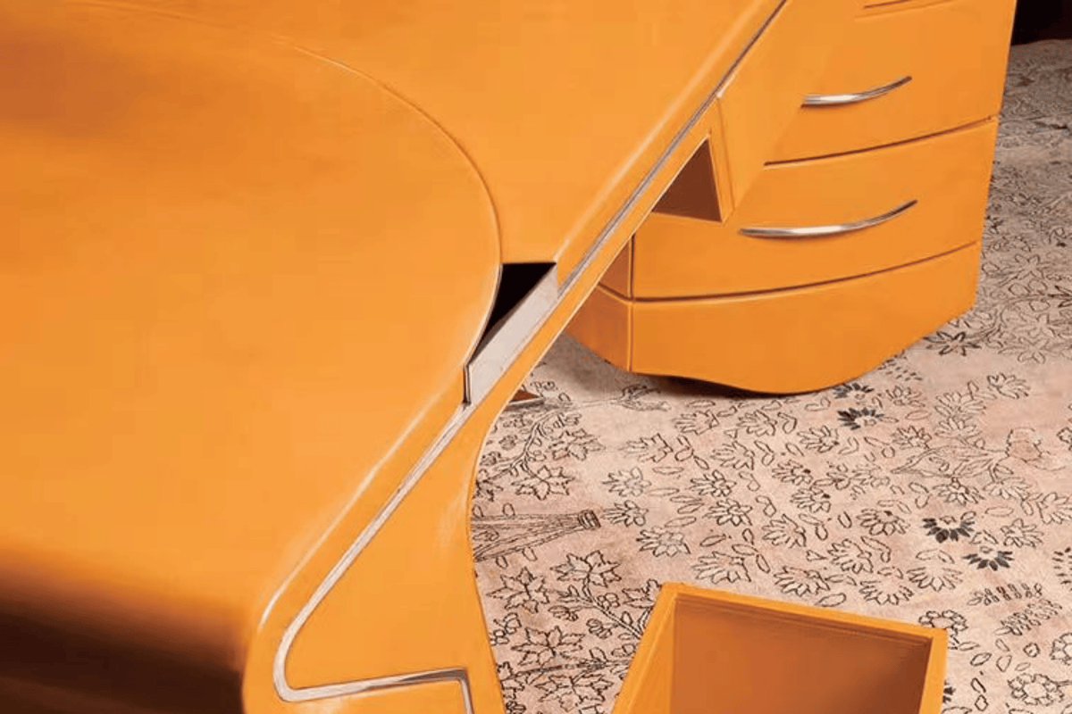 Side view of orange sculptural solid surface executive desk for creative offices with seamless acrylic solid surface finish