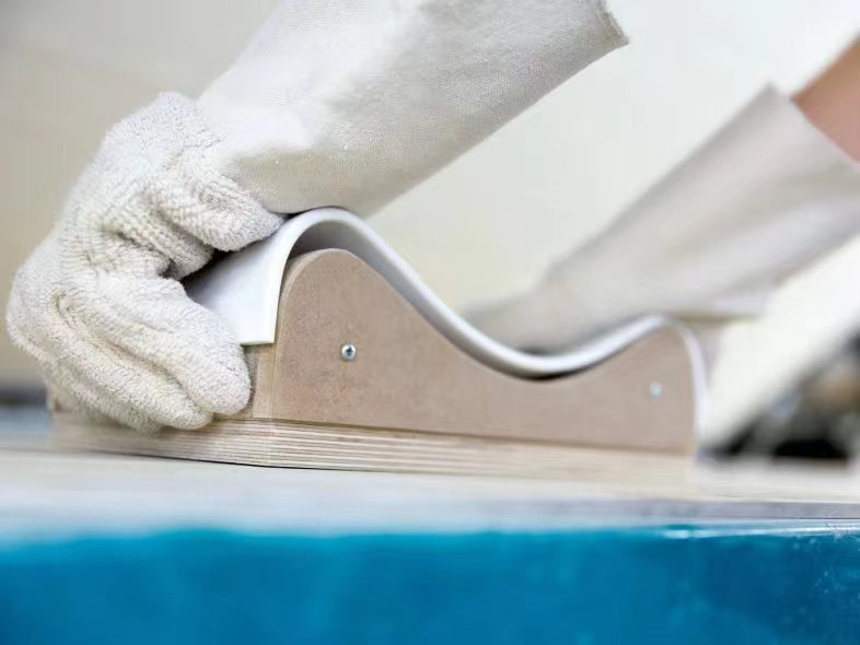 Worker shaping a heated solid surface strip around a curved form