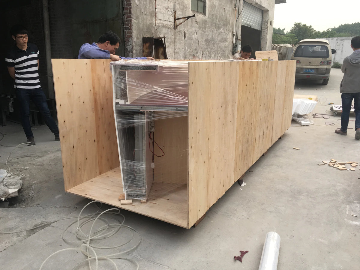 Workers assembling wooden crate panels around a film-wrapped reception counter