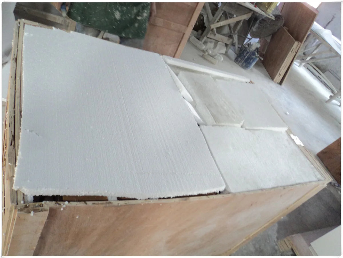 White protective panels placed over a solid surface component inside a wooden crate