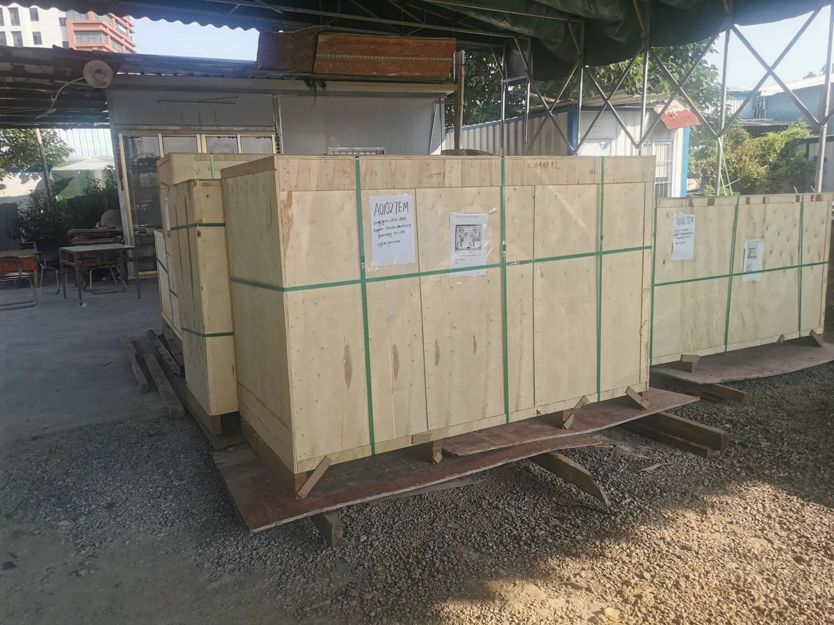 Large wooden export crates secured with green straps and external reference sheets