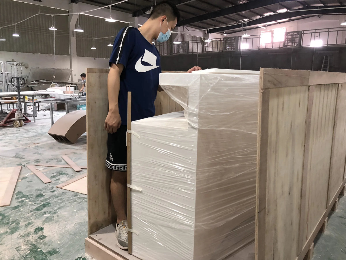 Worker fitting wooden crate panels around a film-wrapped custom reception counter